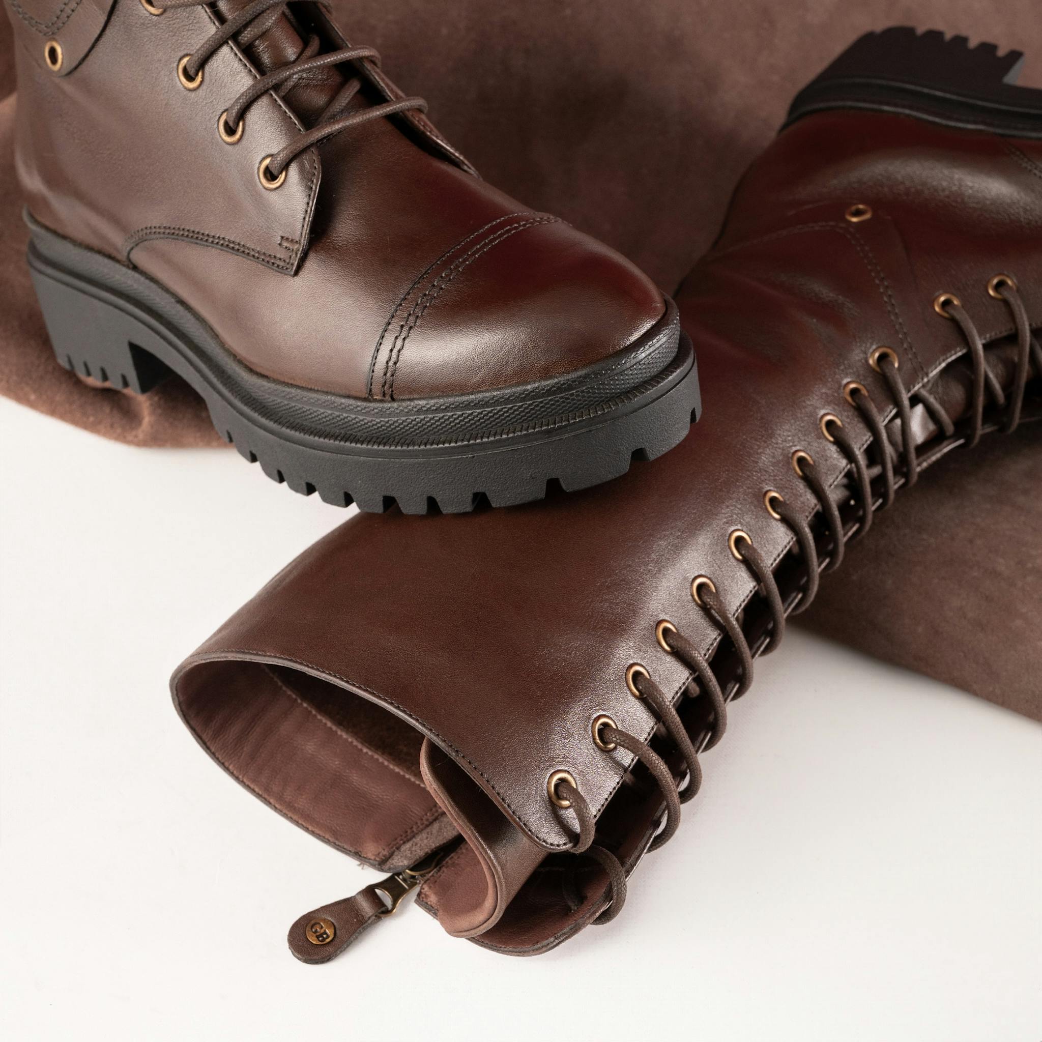 Elegant brown leather knee-high boots featuring lace ties, perfect for a sophisticated fashion look.