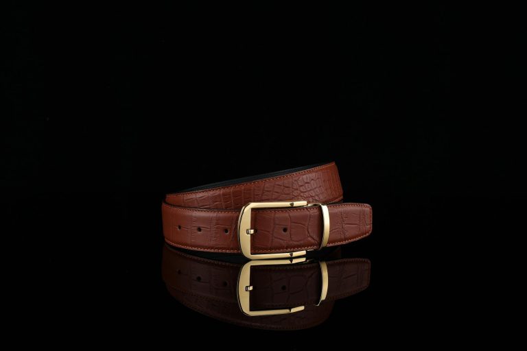 Stylish brown leather belt with a gold buckle on black background.