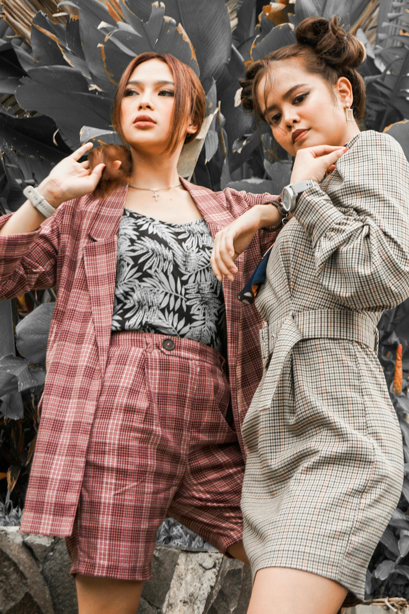Two fashionable Asian women posing confidently in stylish checkered outfits outdoors.